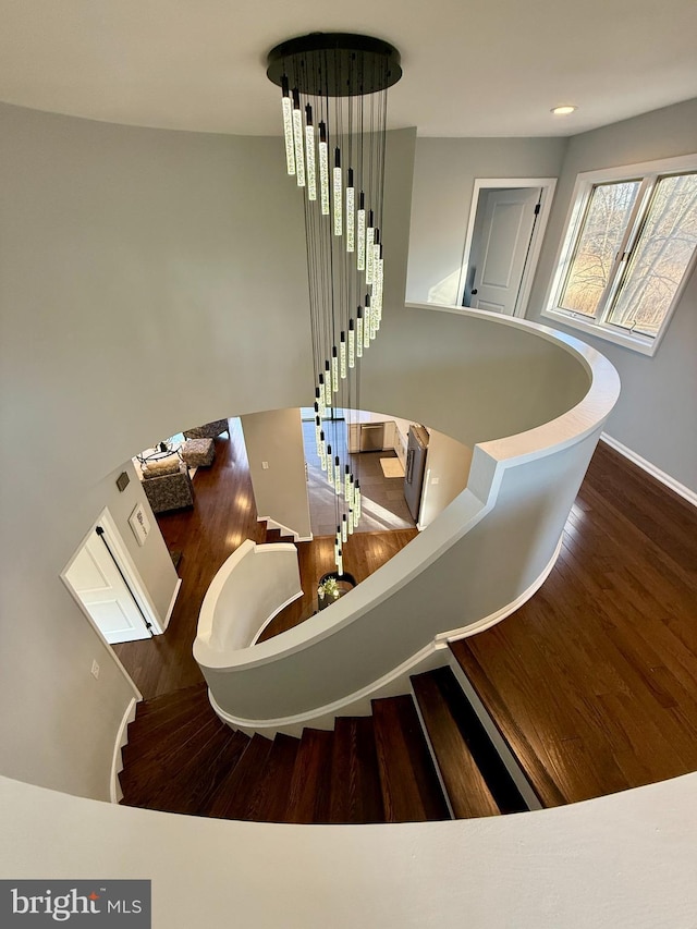 stairs with a chandelier and hardwood / wood-style flooring