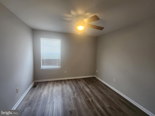 empty room with ceiling fan and dark hardwood / wood-style flooring