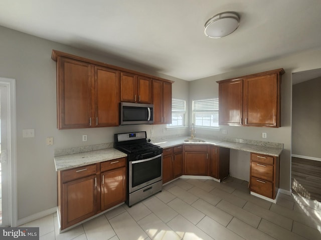 kitchen featuring stainless steel appliances, light stone countertops, and sink