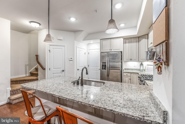 kitchen featuring sink, a breakfast bar area, hanging light fixtures, appliances with stainless steel finishes, and kitchen peninsula