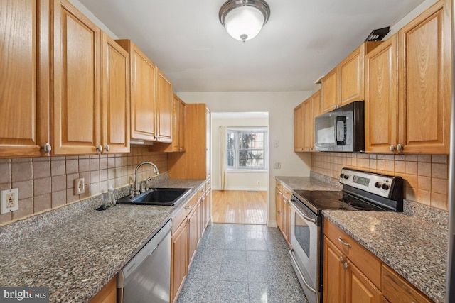 kitchen with dark stone countertops, sink, backsplash, and appliances with stainless steel finishes