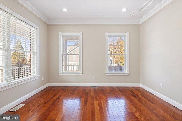 empty room with crown molding, plenty of natural light, and dark hardwood / wood-style floors