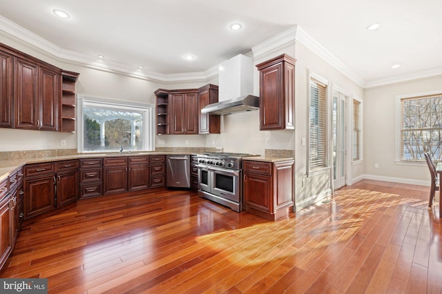 kitchen featuring wall chimney range hood, crown molding, sink, appliances with stainless steel finishes, and hardwood / wood-style floors