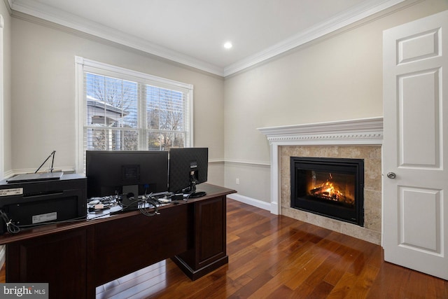 home office with crown molding, dark wood-type flooring, and a tile fireplace