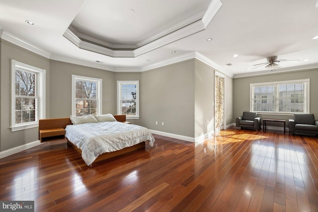 bedroom with dark hardwood / wood-style flooring, a tray ceiling, and crown molding