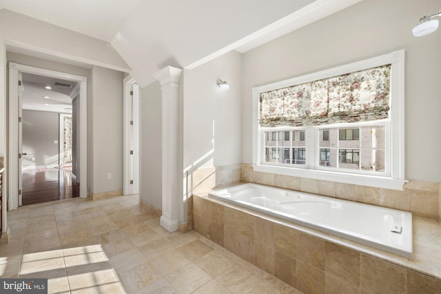 bathroom with decorative columns and tiled bath