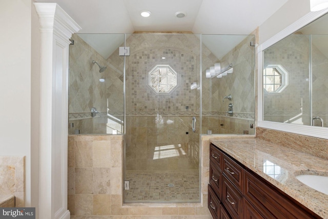 bathroom featuring vanity, lofted ceiling, and a shower with shower door