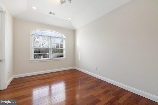 empty room featuring vaulted ceiling and dark hardwood / wood-style floors