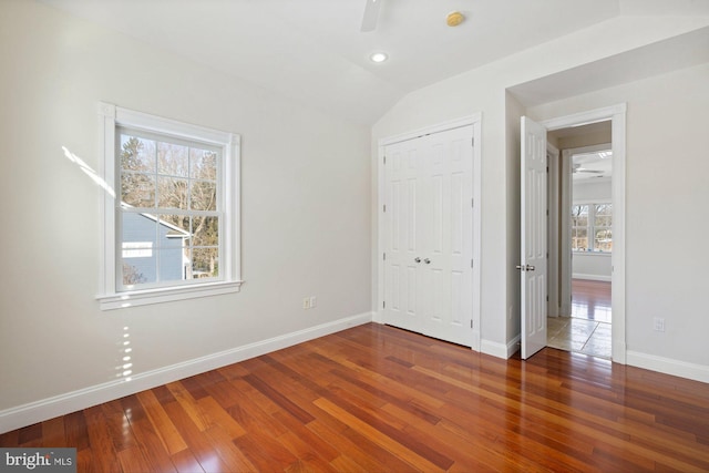 unfurnished bedroom featuring dark wood-type flooring, ceiling fan, lofted ceiling, and a closet