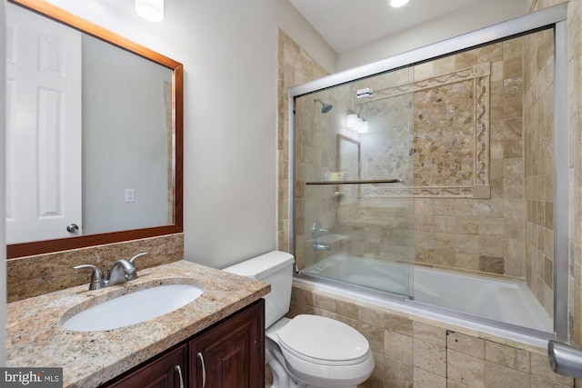 full bathroom with bath / shower combo with glass door, vanity, and toilet