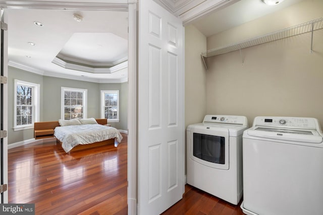 laundry area featuring dark wood-type flooring, ornamental molding, and washer and dryer