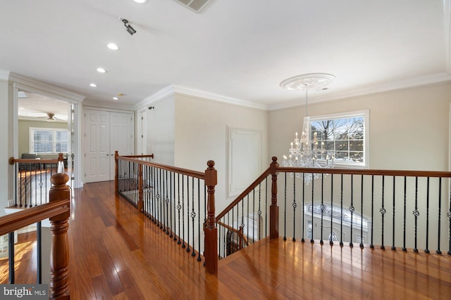 hallway with ornamental molding, hardwood / wood-style floors, and a notable chandelier