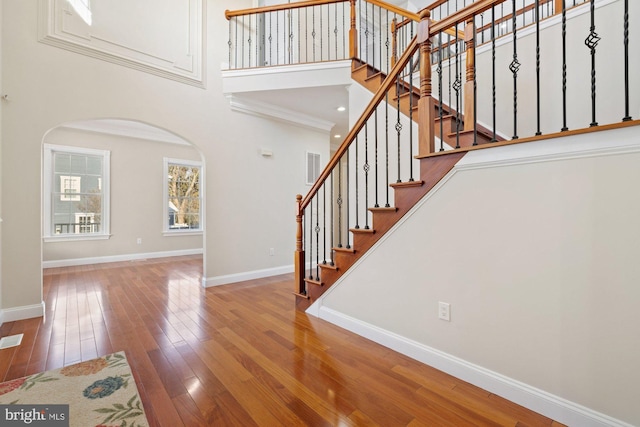 stairway with a towering ceiling and hardwood / wood-style floors