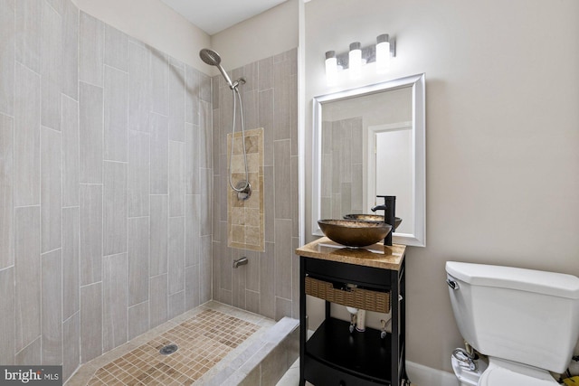 bathroom with a tile shower, sink, and toilet