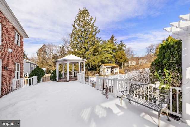 yard covered in snow featuring a gazebo and a storage shed