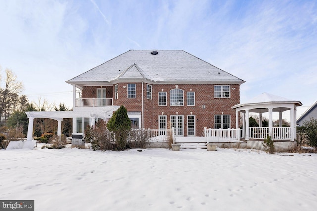 snow covered house featuring a gazebo and a balcony