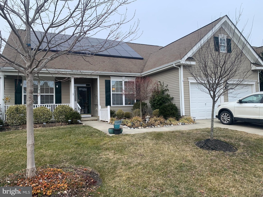 view of front of property with a garage, a front lawn, covered porch, and solar panels