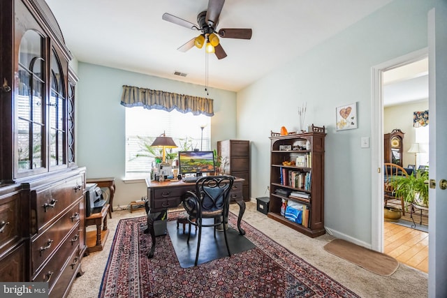 office space featuring carpet flooring, baseboards, visible vents, and ceiling fan