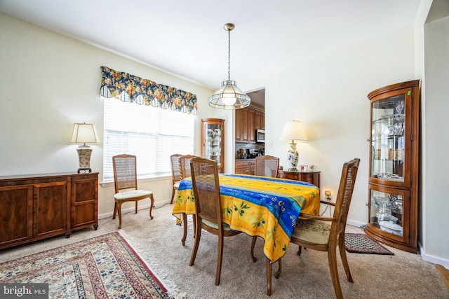 dining space with baseboards and light colored carpet