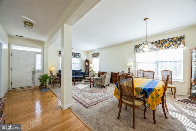 dining space featuring light wood finished floors, visible vents, and baseboards