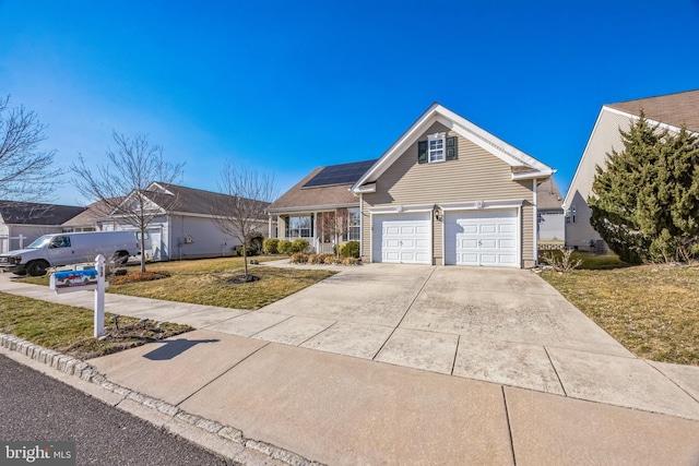 traditional-style home with solar panels, a front yard, and driveway