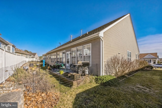 rear view of property featuring a residential view, a lawn, and fence