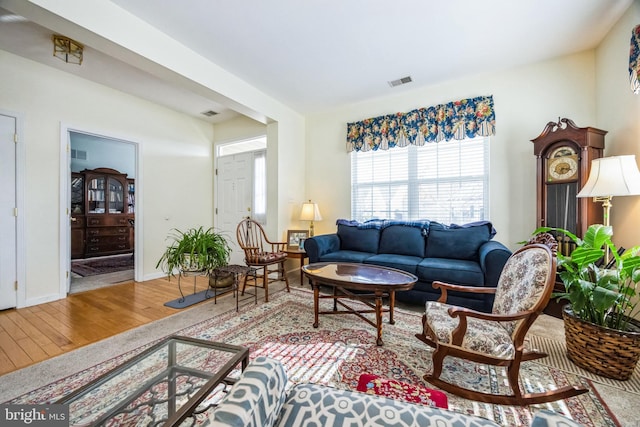 living area with visible vents, baseboards, and wood finished floors