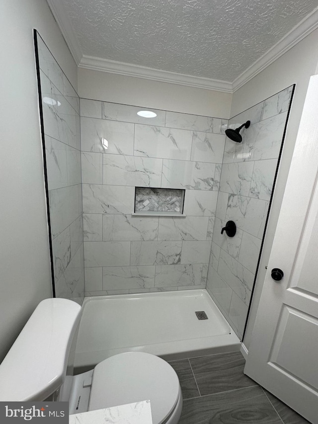 bathroom featuring crown molding, tiled shower, a textured ceiling, and toilet