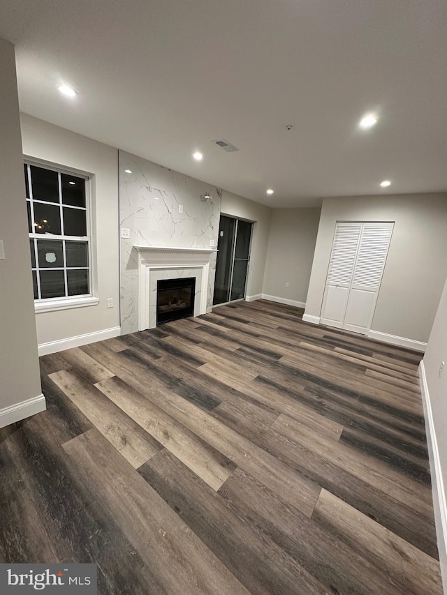 unfurnished living room featuring a high end fireplace and dark hardwood / wood-style floors