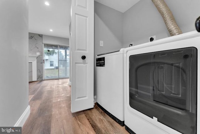 laundry room with wood-type flooring, washer / dryer, and a high end fireplace