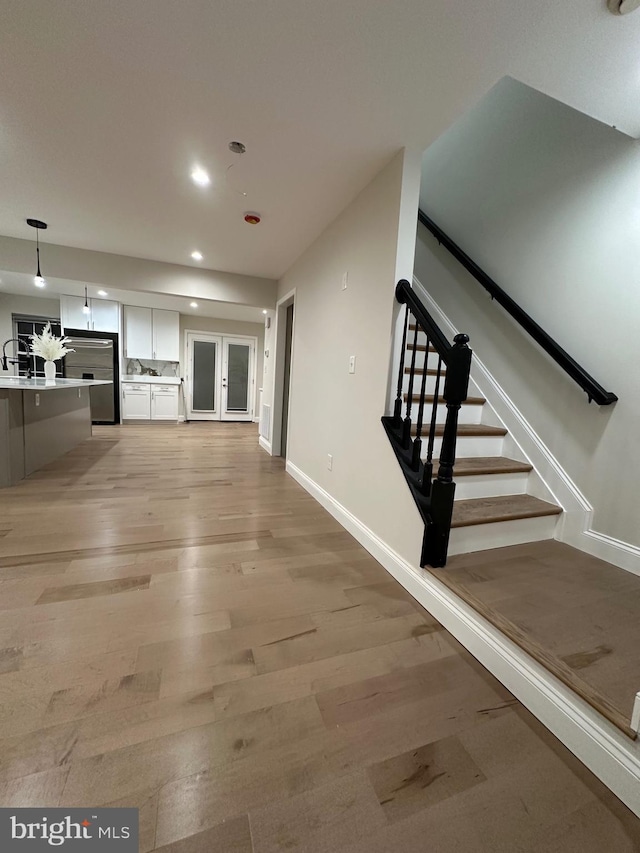 kitchen with white cabinetry, decorative light fixtures, and light hardwood / wood-style floors