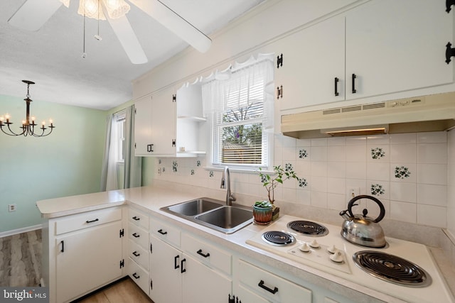 kitchen with pendant lighting, sink, white cooktop, white cabinets, and kitchen peninsula