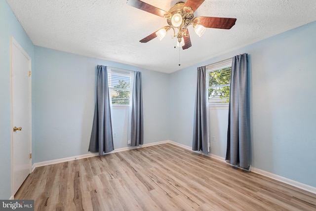 empty room with plenty of natural light, a textured ceiling, and light wood-type flooring