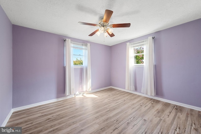 unfurnished room with ceiling fan, light hardwood / wood-style flooring, and a textured ceiling