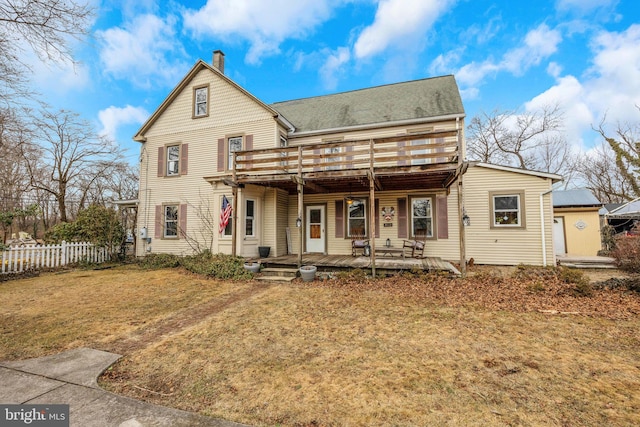 back of property featuring a wooden deck and a yard