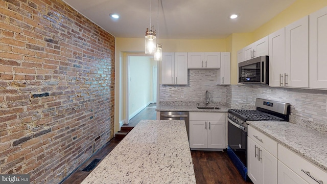 kitchen featuring sink, white cabinets, hanging light fixtures, light stone countertops, and appliances with stainless steel finishes