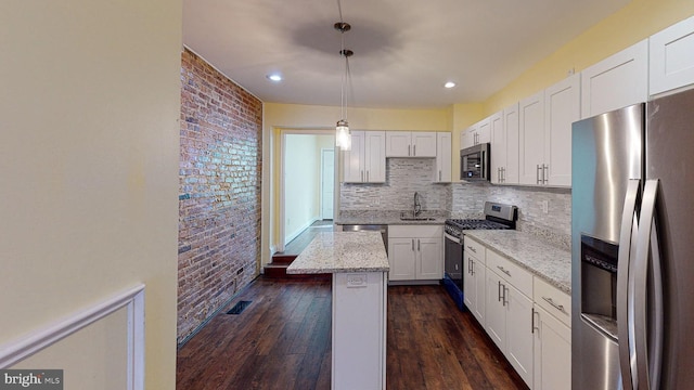 kitchen with light stone counters, pendant lighting, a center island, stainless steel appliances, and white cabinetry