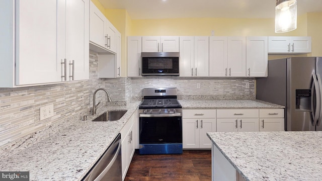 kitchen with white cabinets, stainless steel appliances, decorative light fixtures, and backsplash