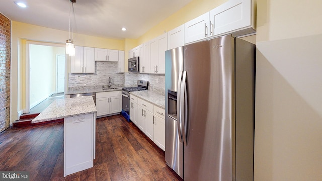 kitchen featuring stainless steel appliances, white cabinetry, light stone counters, hanging light fixtures, and a kitchen island