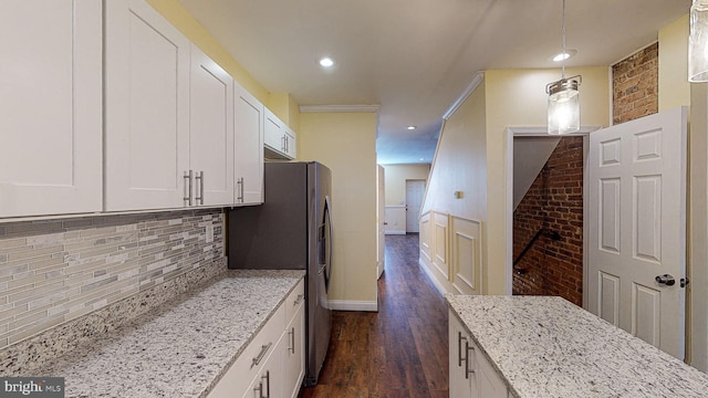 kitchen featuring white cabinetry, light stone countertops, decorative backsplash, hanging light fixtures, and dark hardwood / wood-style floors