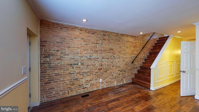 spare room with hardwood / wood-style floors, crown molding, and brick wall