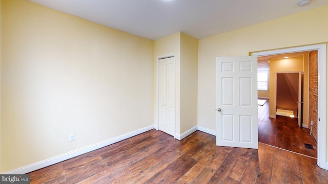 unfurnished bedroom with dark wood-type flooring and a closet