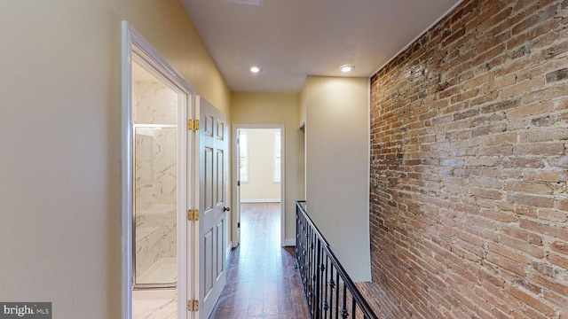 hallway with brick wall and wood-type flooring