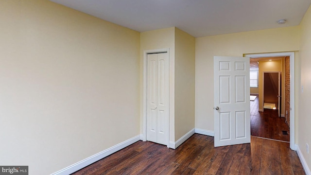 unfurnished bedroom with a closet and dark wood-type flooring