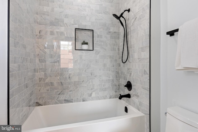 bathroom featuring tiled shower / bath combo and toilet