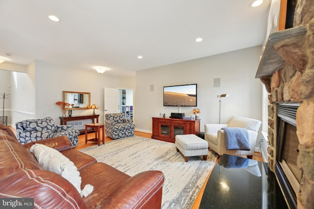 living room with recessed lighting, baseboards, wood finished floors, and a stone fireplace