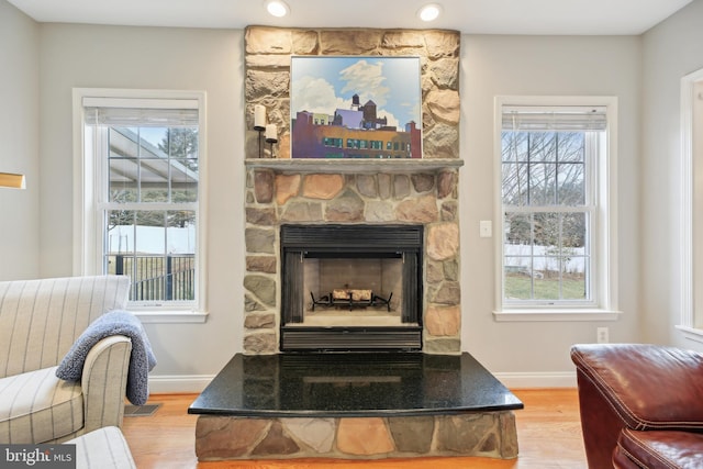 details with a stone fireplace, recessed lighting, wood finished floors, and baseboards