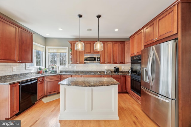 kitchen featuring brown cabinets, light wood-style flooring, and black appliances