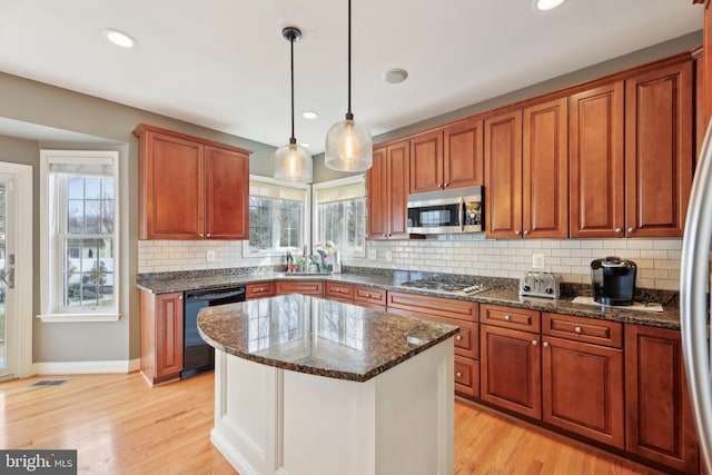 kitchen featuring stainless steel appliances, visible vents, light wood-type flooring, dark stone countertops, and pendant lighting