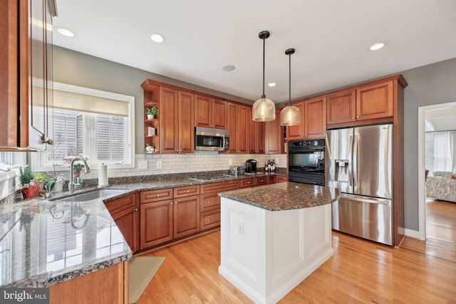 kitchen featuring stainless steel appliances, a sink, light wood-type flooring, tasteful backsplash, and brown cabinetry